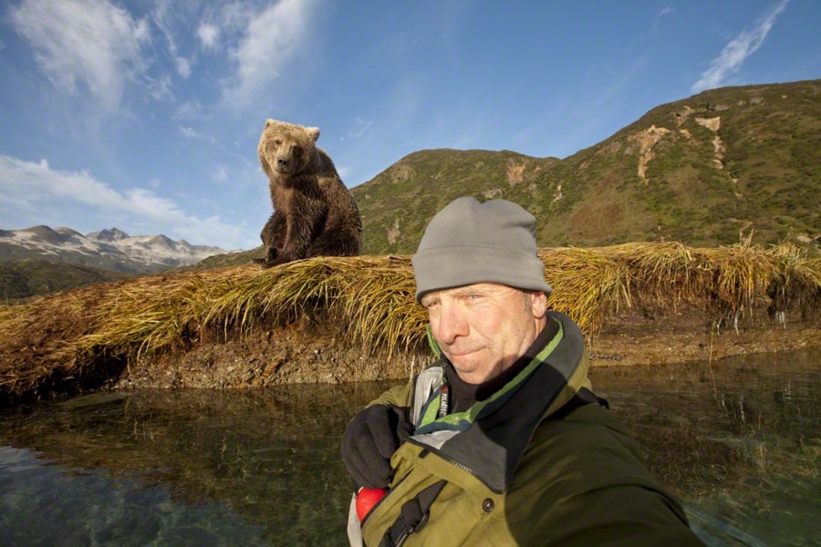 мужчина делает селфи на фоне медведя