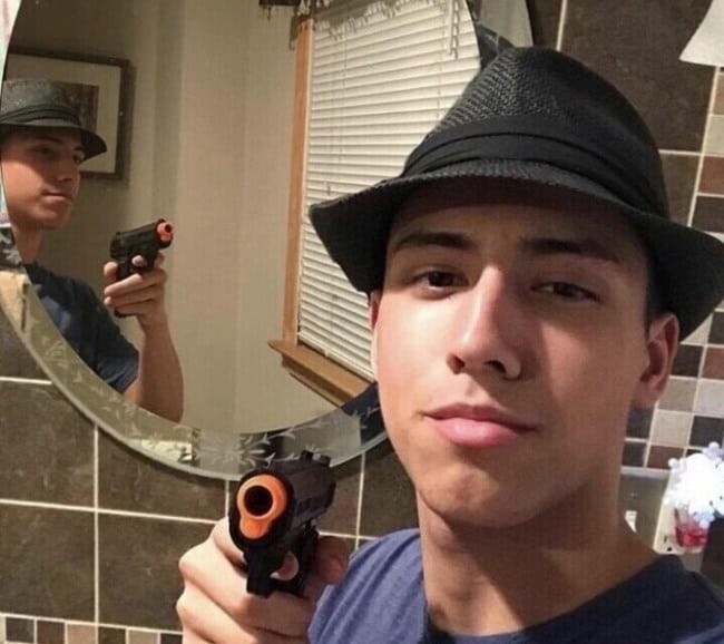 парень в шляпе и с пистолетом