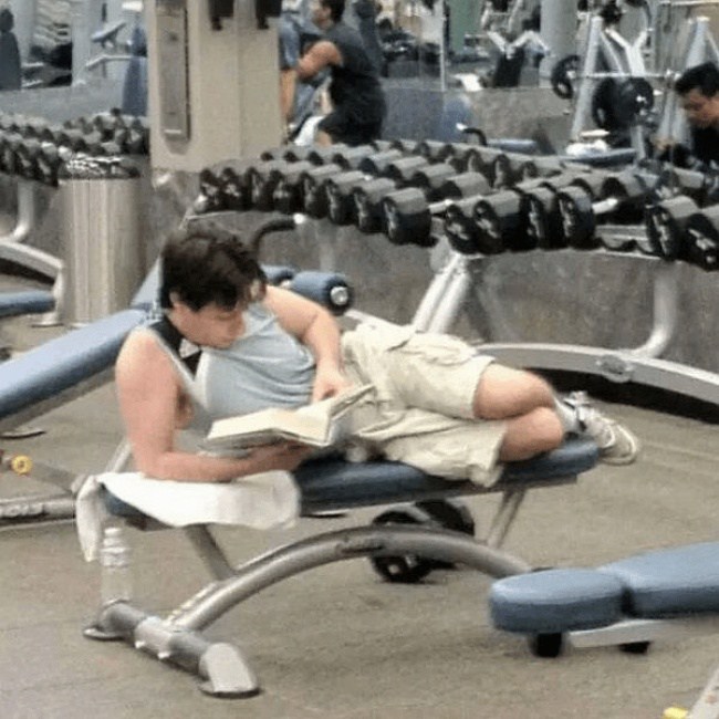 парень читает книгу в спортзале