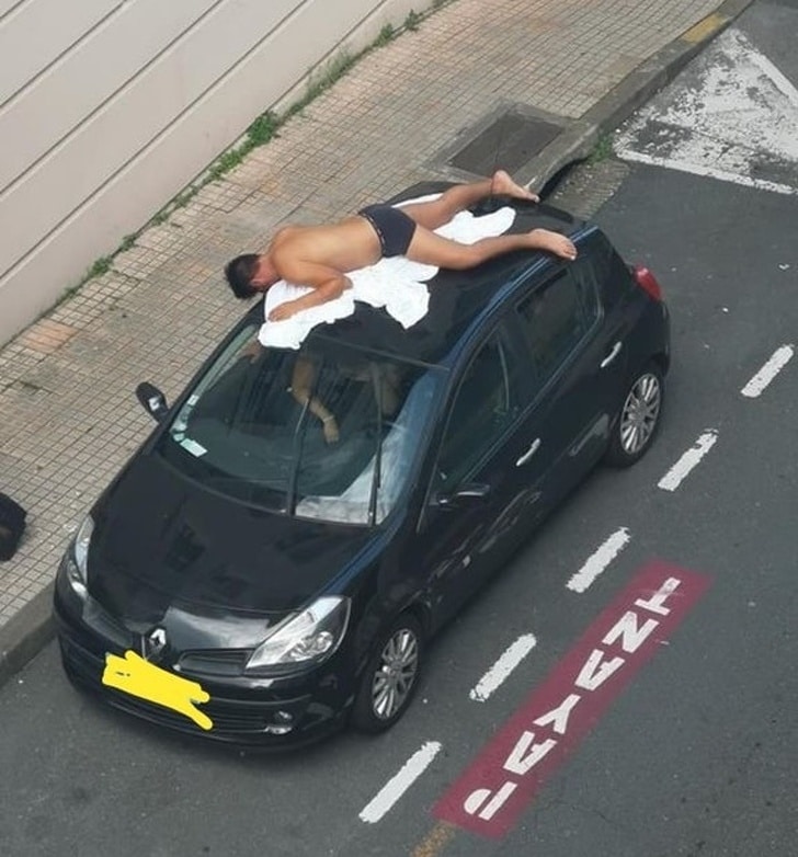 парень загорает на крыше автомобиля
