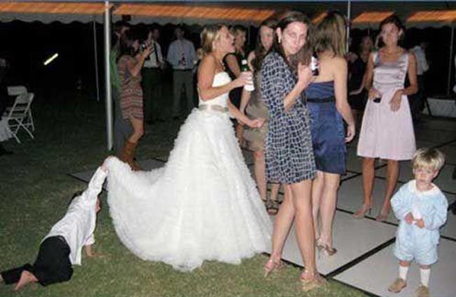 мальчик заглядывает под платье невесты