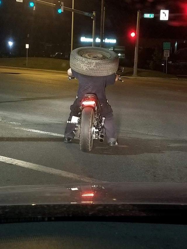мотоциклист с колесом на голове