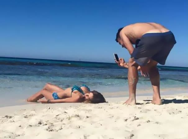 парень фотографирует девушку на песке