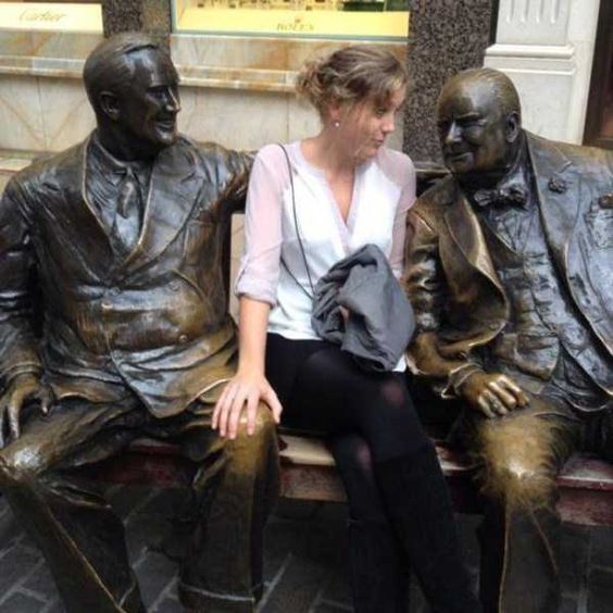 девушка сидит рядом со скульптурой мужчинам