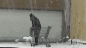 мужчина собирает лопатой снег