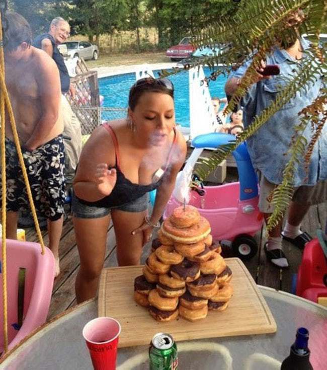 девушка задувает свечу на пончиках