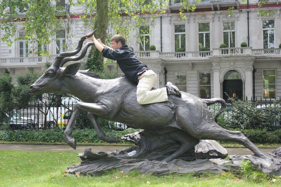 парень верхом на памятнике антилопе
