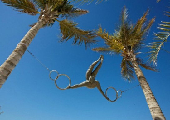 скульптура воздушного гимнаста между пальмами