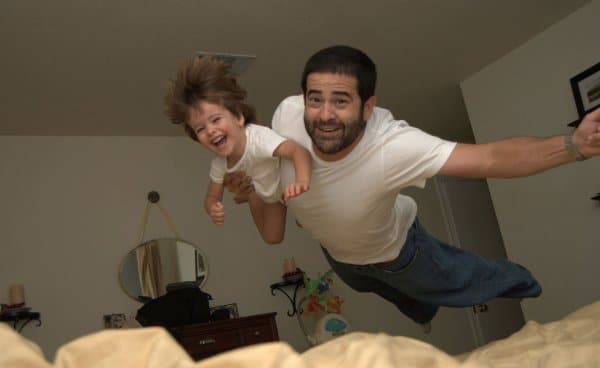 папа с ребенком прыгают на кровать