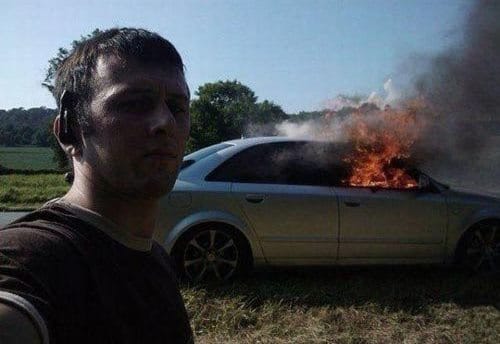 мужчина делает селфи на фоне горящей машины