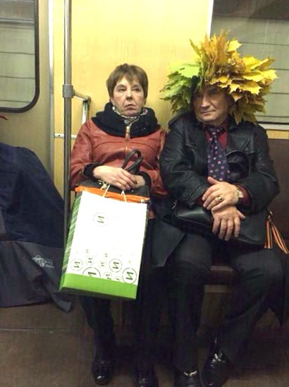женщина сидит в метро с мужчиной у которого на голове листья
