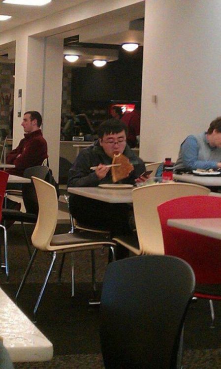 парень ест пиццу палочками