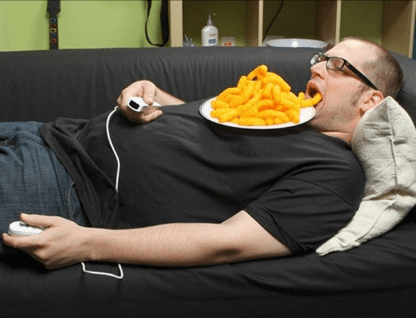 мужчина ест, лежа на диване