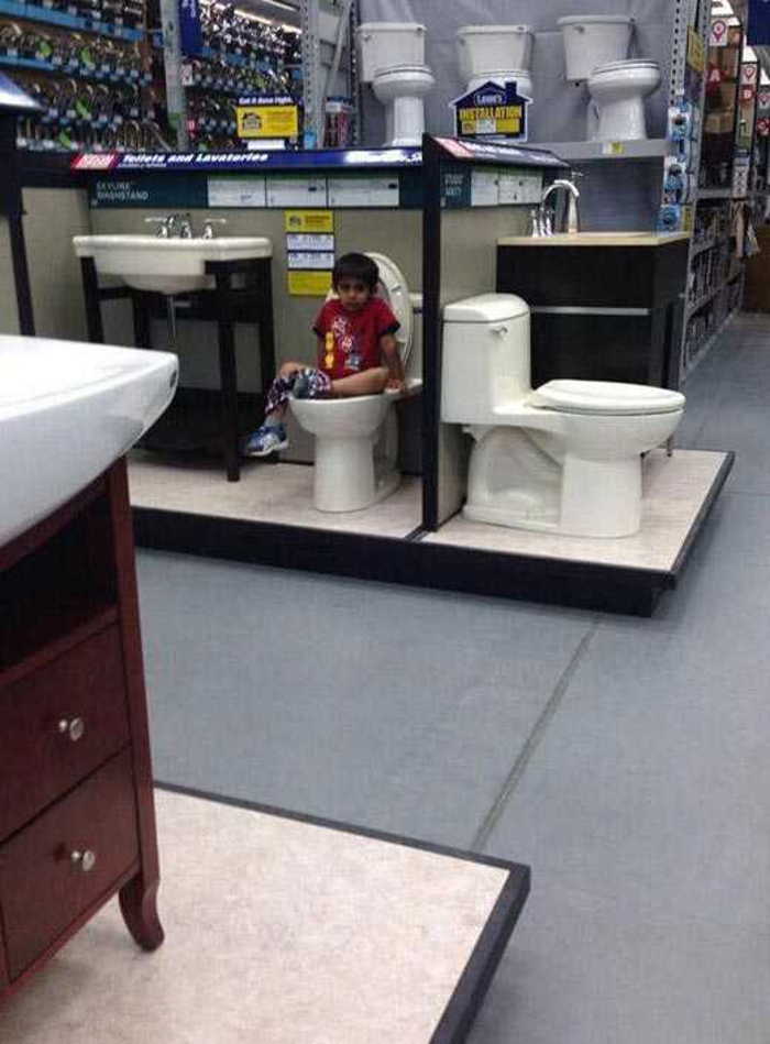 мальчик сидит на унитазе в магазине сантехники