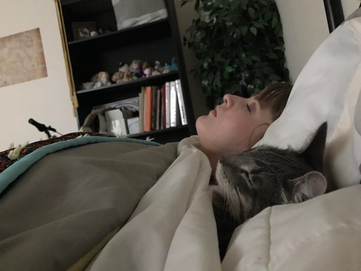 кот спит в кровати с девушкой