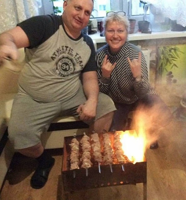 муж и жена жарят шашлыки на мангале в кухне