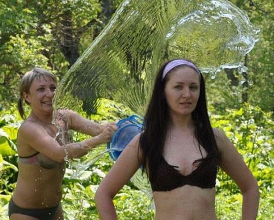 девушка обливает подругу водой со спины