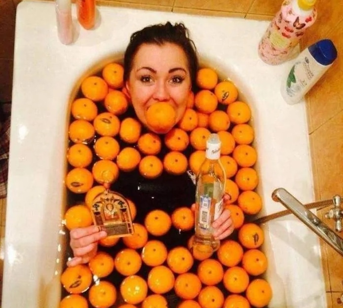 девушка лежит в ванне с апельсинами