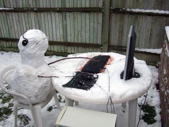 снеговик сидит за столом с ноутбуком
