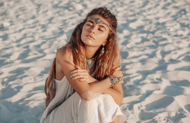 девушка сидит на песке с закрытыми глазами