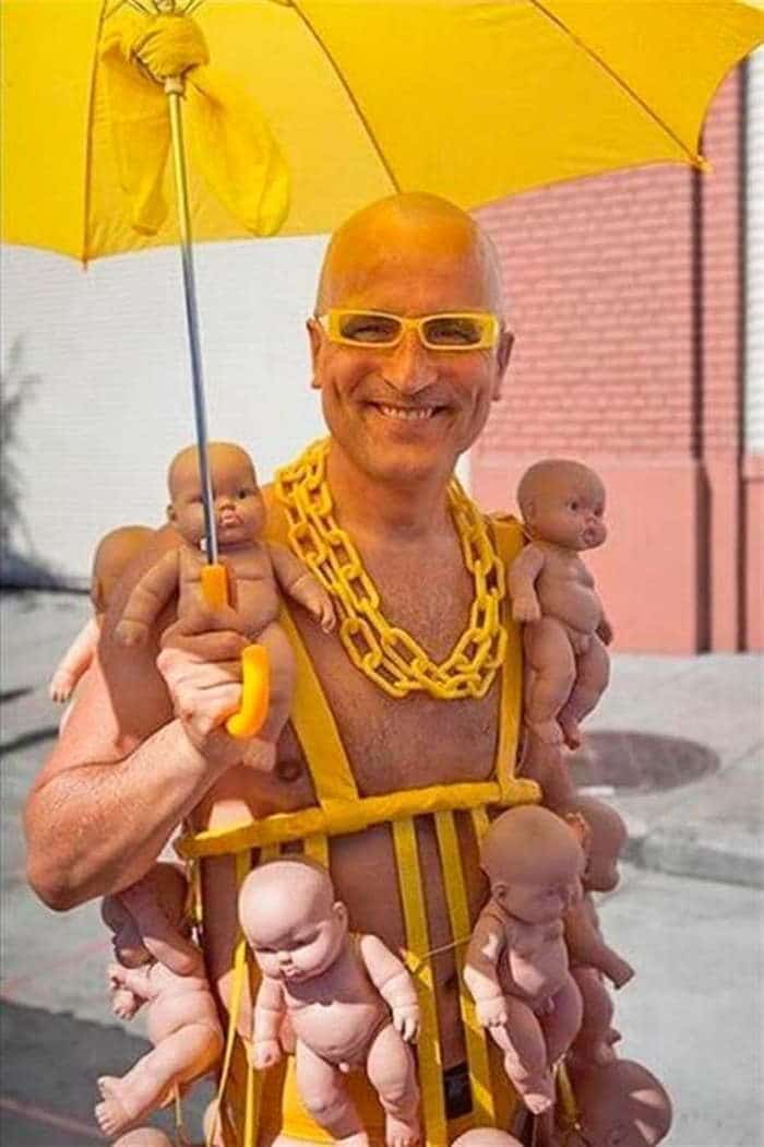 мужчина с куклами под желтым зонтом