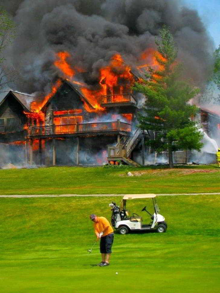 мужчина играет в гольф на фоне горящего дома