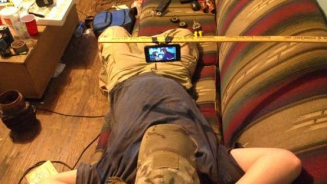 парень смотрит видео на телефоне, лежа на диване