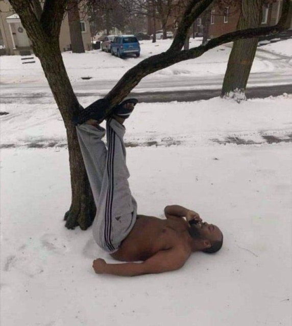 чернокожий мужчина лежит с телефоном в снегу
