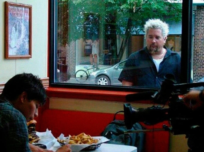 мужчина смотрит через окно на картошку фри