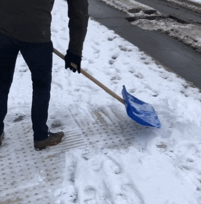 мужчина чистит лопатой снег