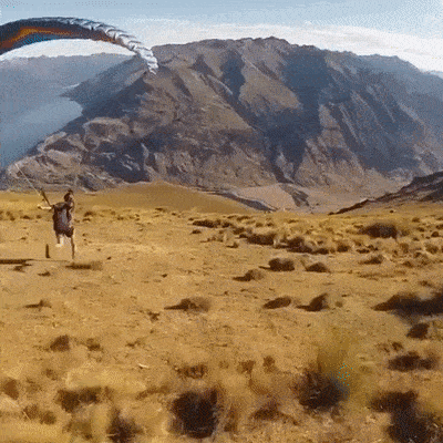 парень прыгает с парашютом с горы