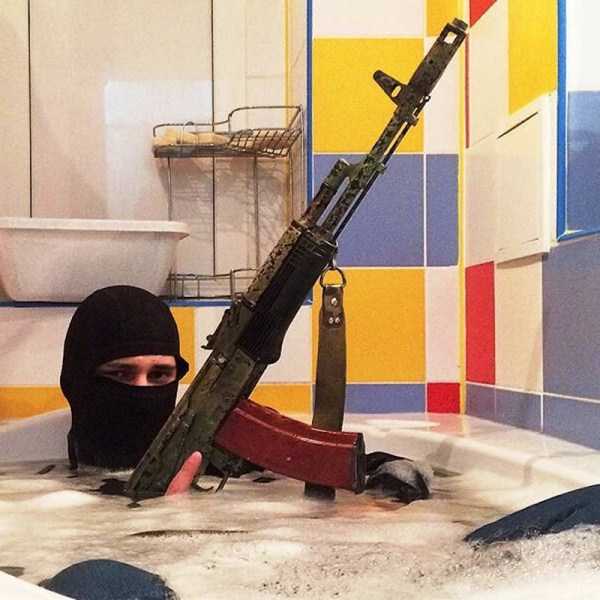 парень в балаклаве с оружием в ванне