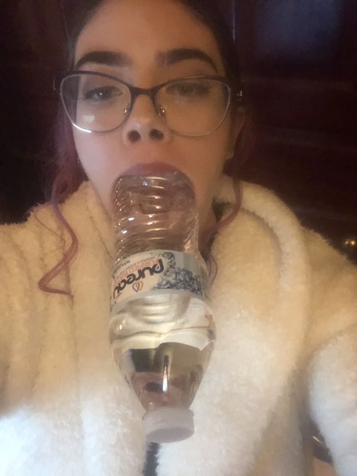 девушка в очках с бутылкой во рту
