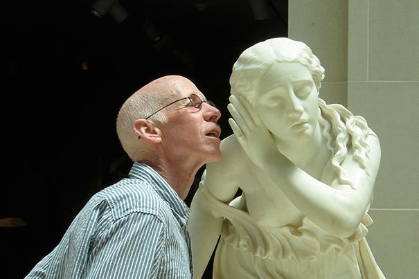 пожилой мужчина рядом со скульптурой