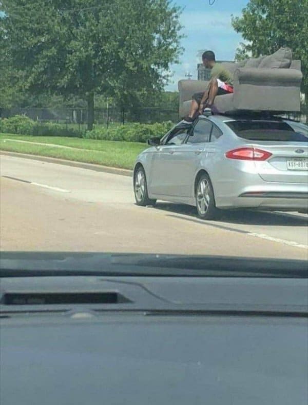 парень едет на диване на крыше авто