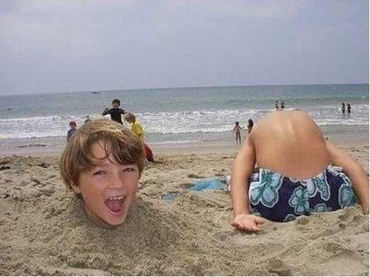 мальчик закопан в песок на пляже