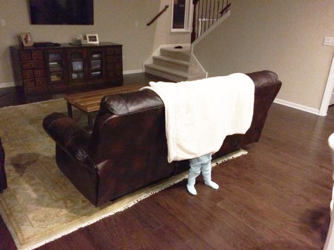ребенок прячется за диваном