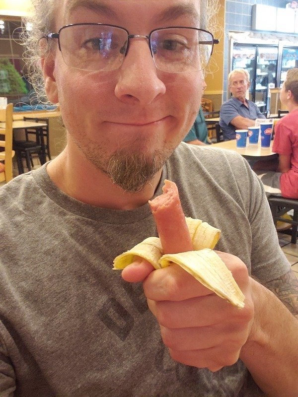 мужчина держит сосиску в банановой кожуре
