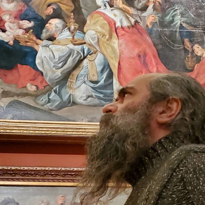 бородатый мужчина на фоне картины