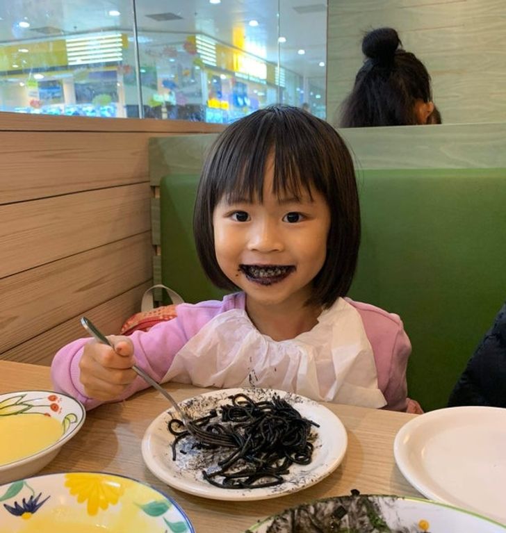 девочка японской внешности ест черные макароны