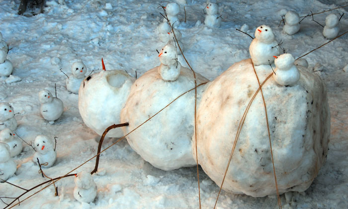 маленькие снеговики сидят на лежащем большом