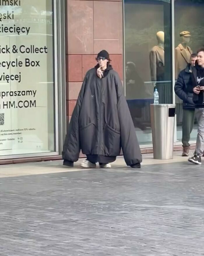 парень в огромной черной куртке на улице