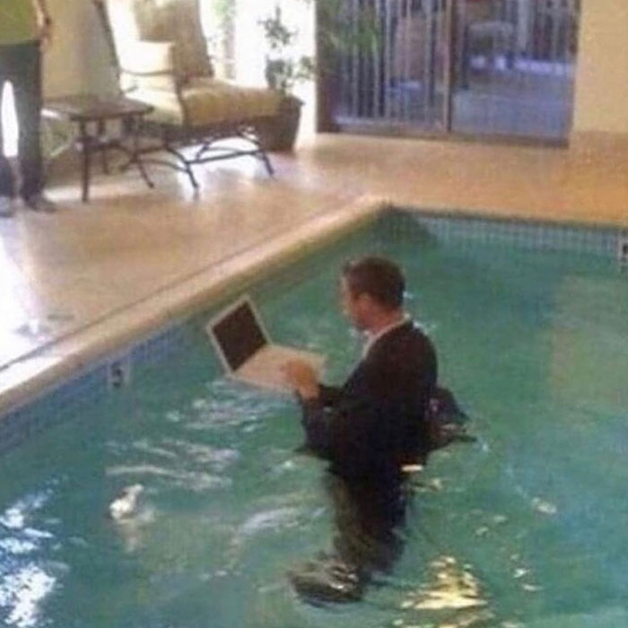 мужчина с ноутбуком стоит в бассейне