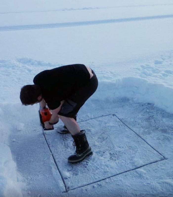 мужчина делает прорубь во льду
