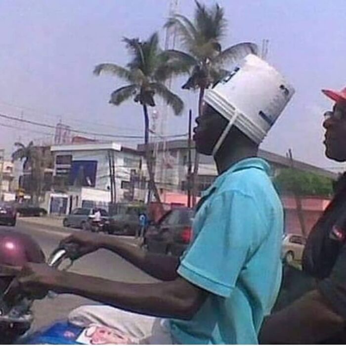чернокожий парень за рулем с ведром на голове